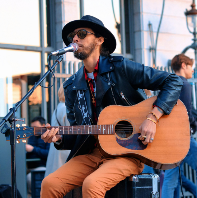 Musician at a concert event playing guitar and singing into a mic