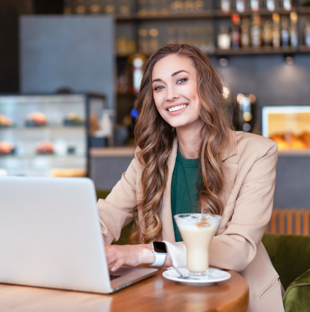 Women at a café sitting at her laptop drinking a coffee